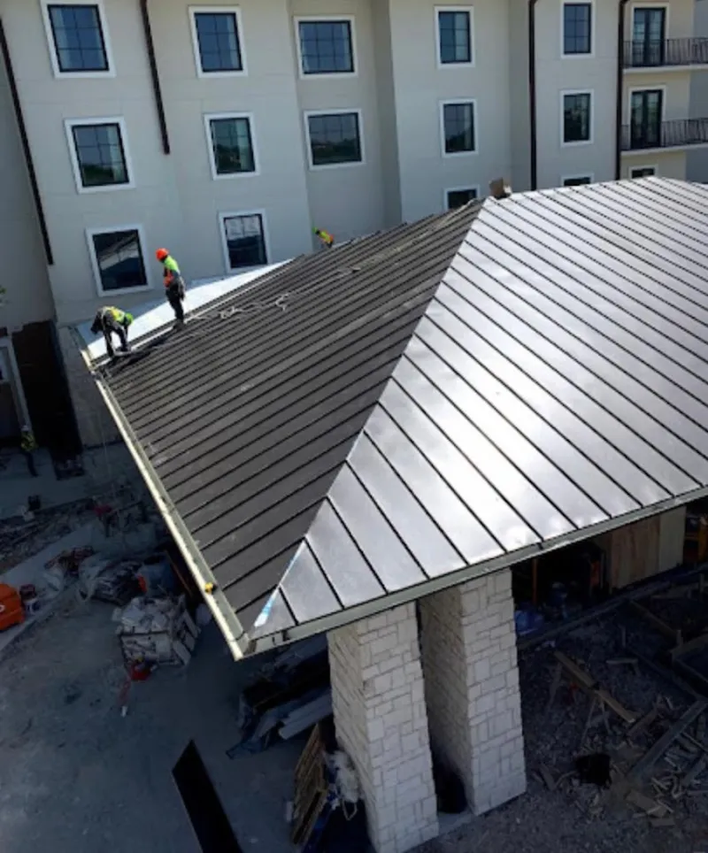 Crew installing standing seam metal roof panels on a commercial project in Horizon West